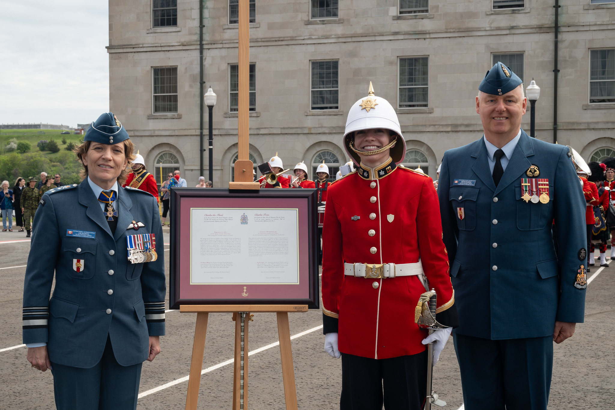 An officer cadet poses for the presentation of a commission script with a General Officer and Chief Warrant Officer 